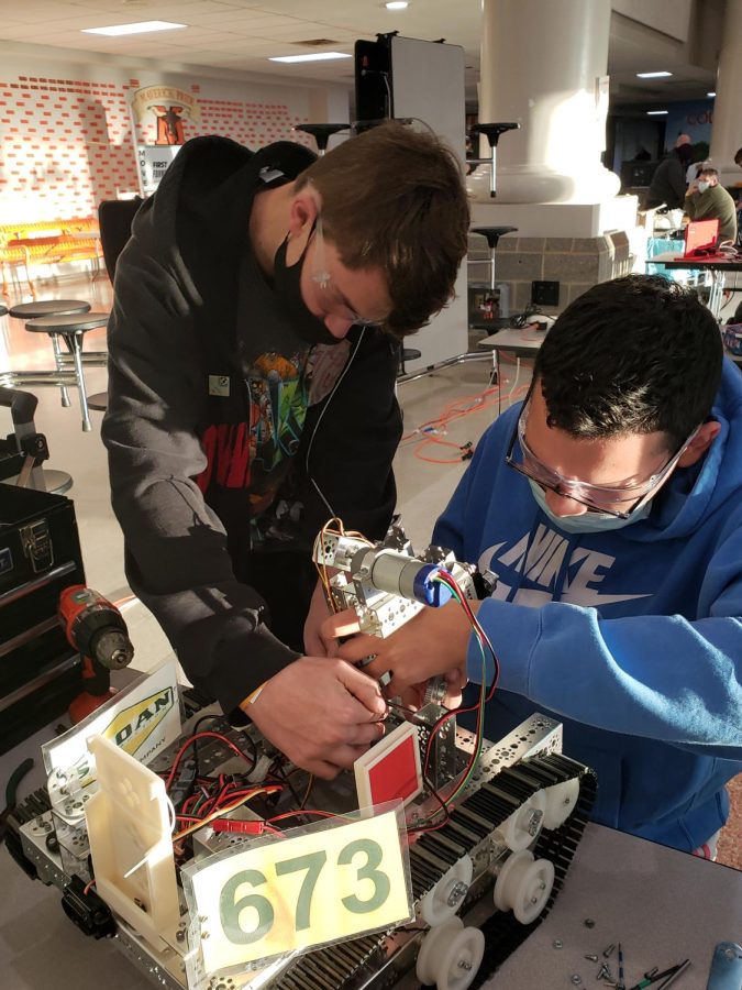 Christian Rodriguez and Alex Lamb working on the robot during a competition 